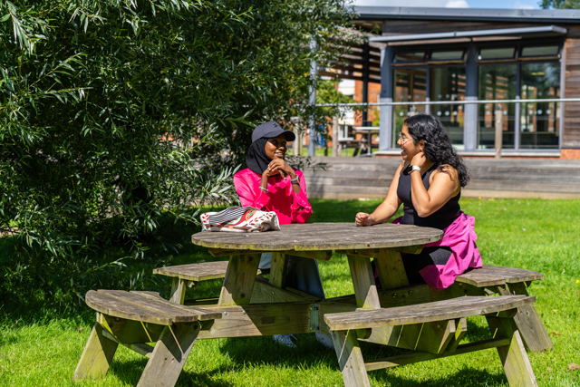Two students sat on bench outside