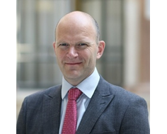 Bald male in suit and tie smiling at camera
