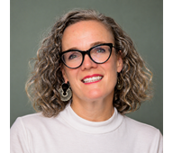 Head shot of woman with glasses a curly haired bob and red lipstick