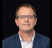 Brown haired male with glasses smiling 