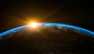 a satellite view of earth, with the sun rising behind