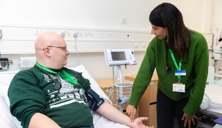 A female physician associate student takes the pulse of a male student acting as a patient