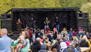 A crowd of people watching and dancing to a band playing on stage