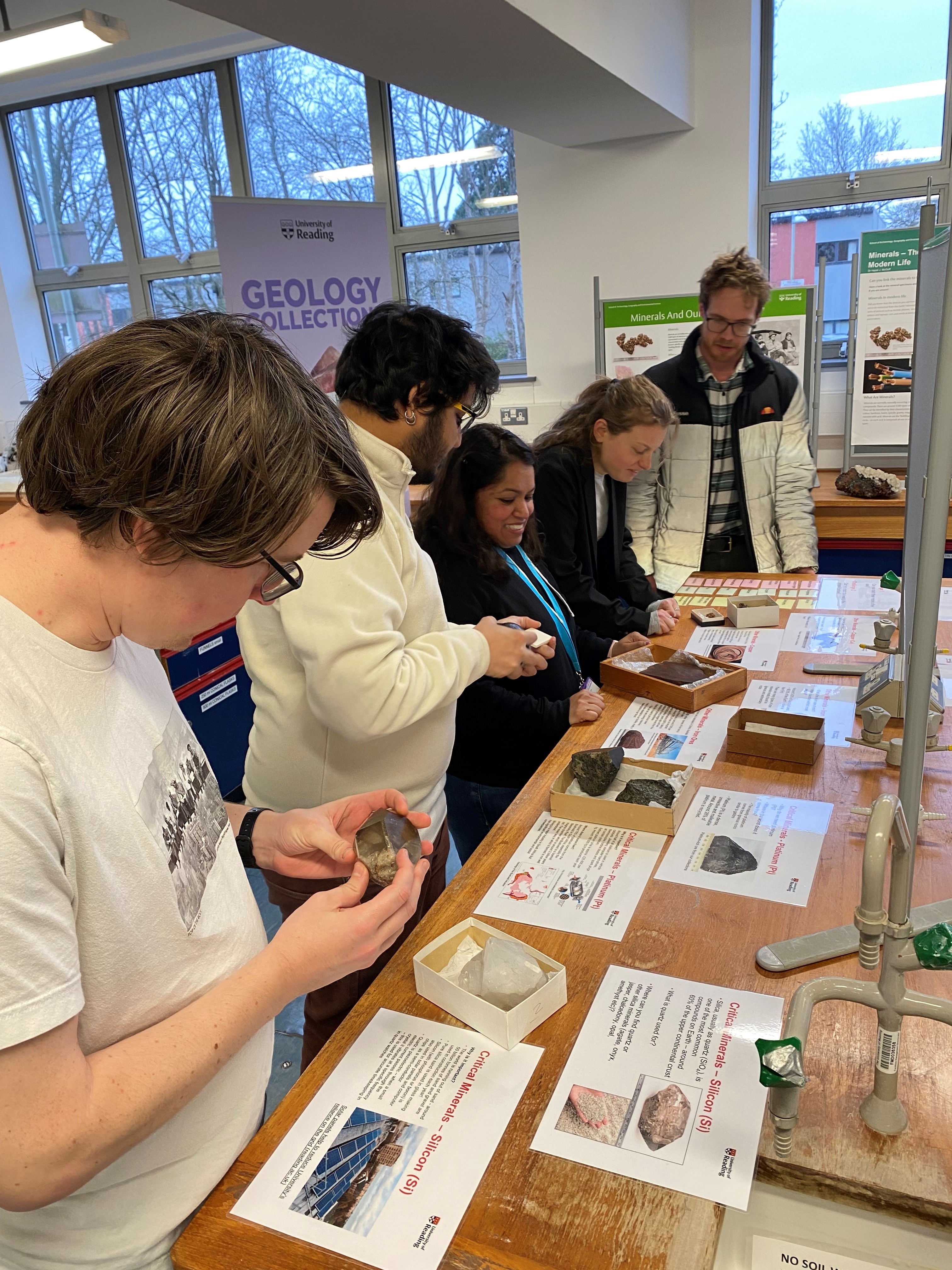 A group of people handling mineral specimens at a display table