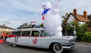 A Ghostbusters car with a giant inflatable marshmallow man next to it