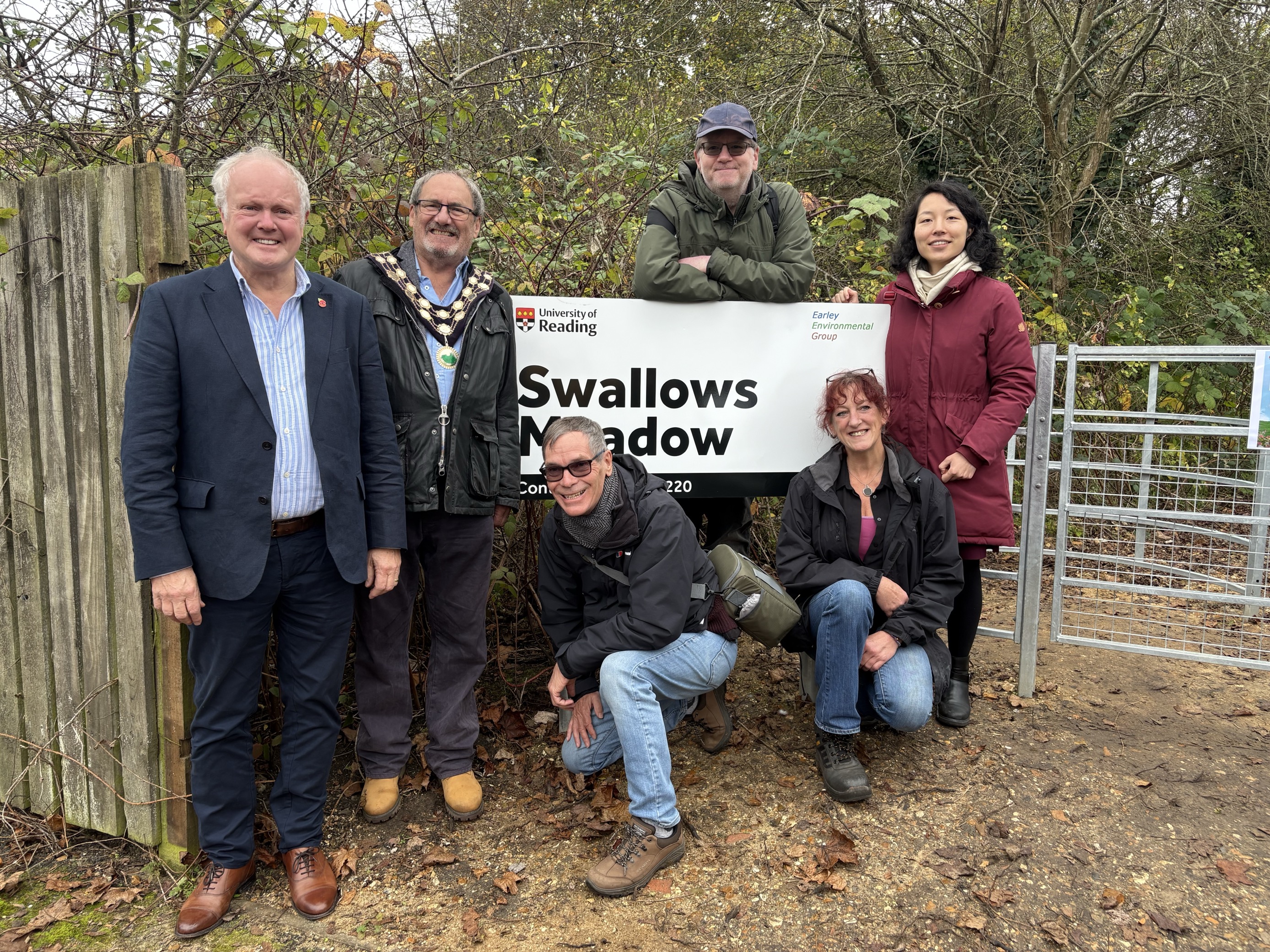 A group of men and women stand around a new sign to mark the opening of a new public amenity, Swallows Meadow