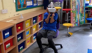 A young girl wearing a virtual reality headset in a school classroom