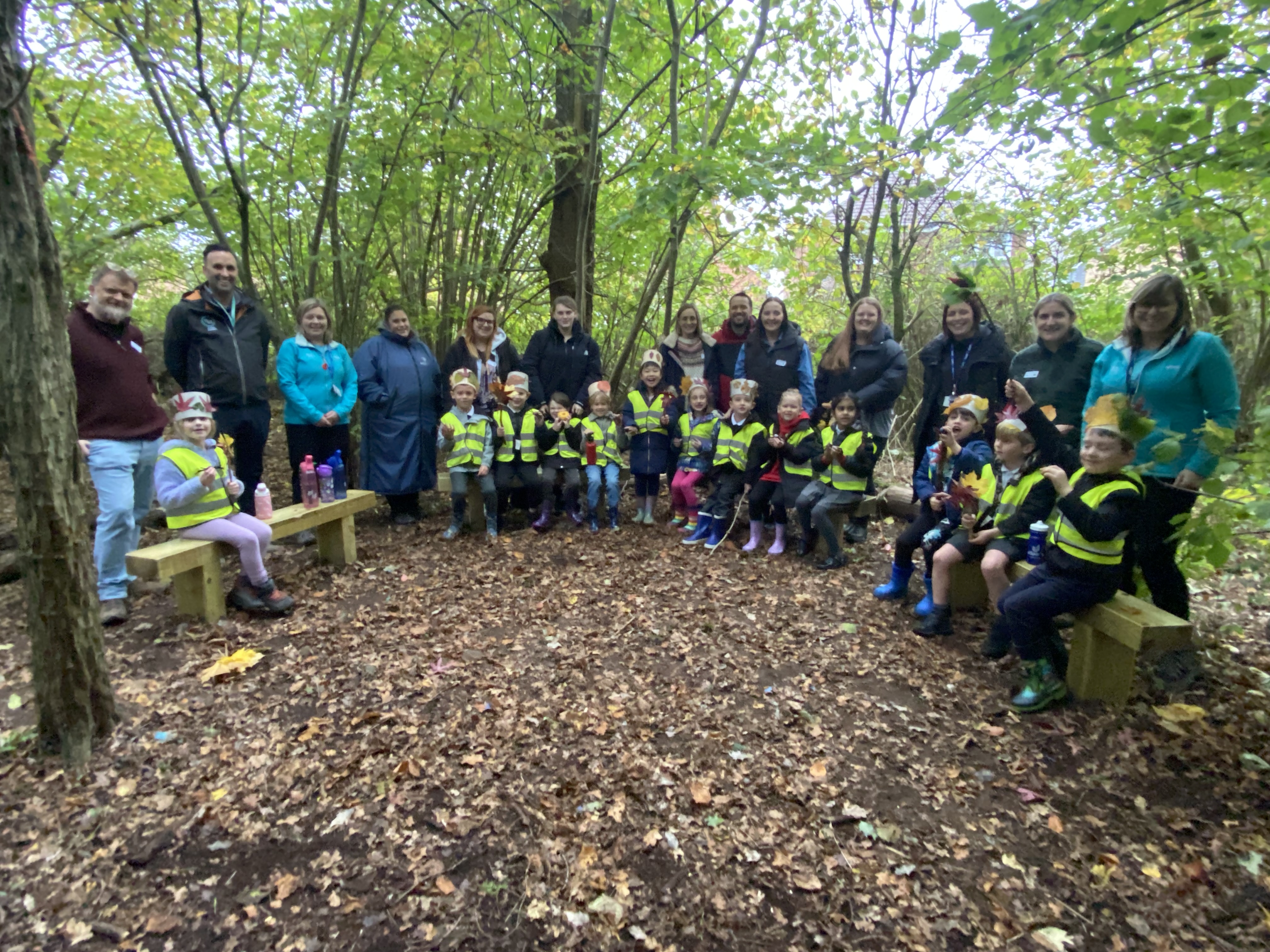 School children and teachers pose in a woodland setting