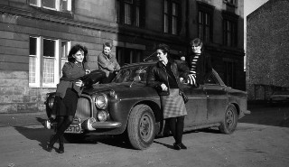 Four white women posing next to a car, image is from the 1980s