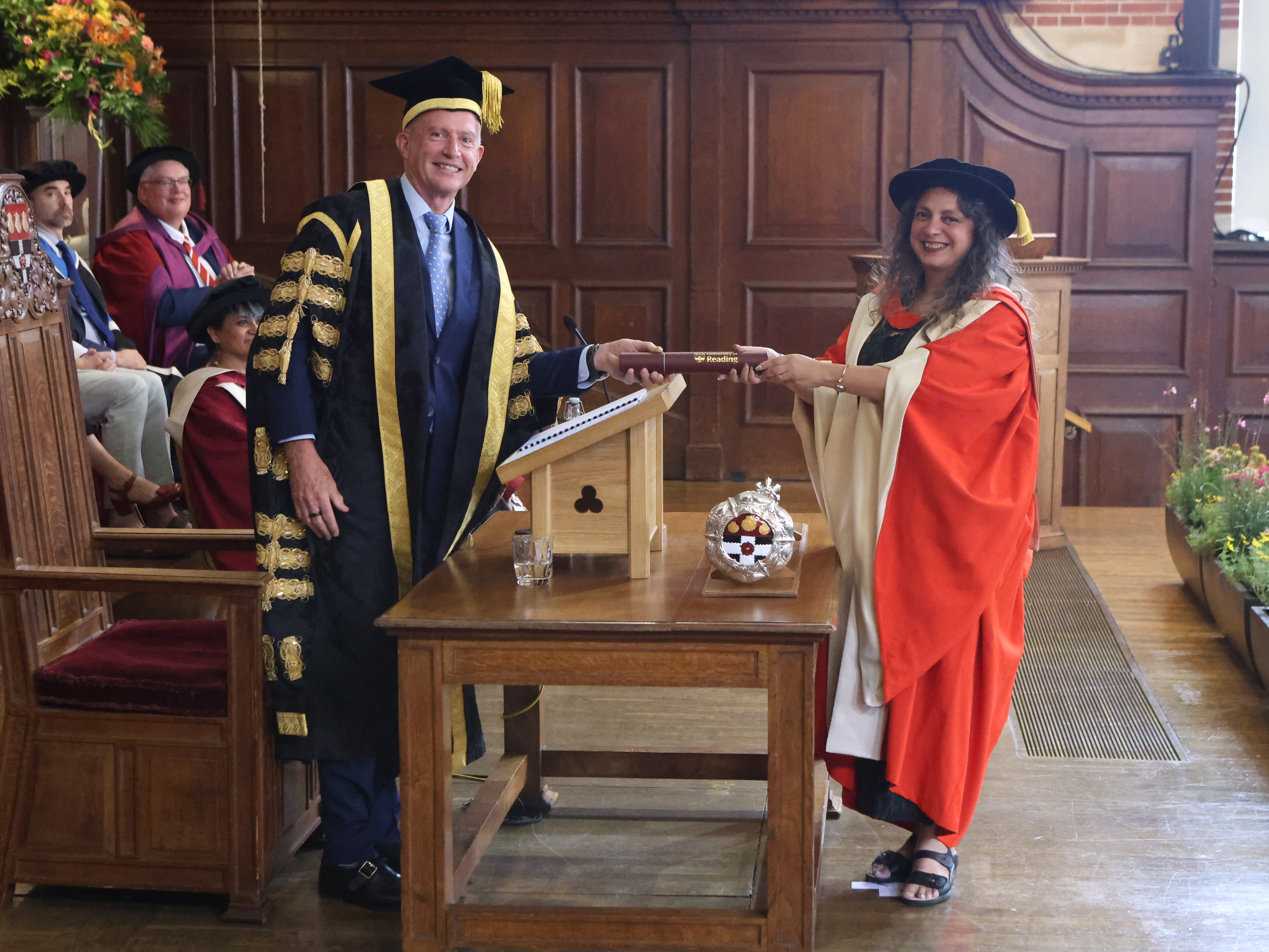 The University Chancellor hands Dom Unsworth her honorary degree on stage