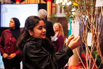 A student hanging a written pledge on a tree in the Great Hall
