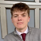 A young man with short, brown hair wearing a shirt and tie