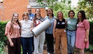 Group of people holding a large metal cylinder capsule