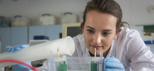 Lab technician in white coat examining scientific utensils