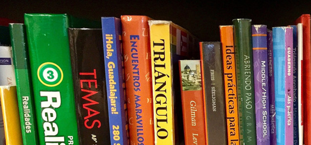 A row of multi coloured book spines on a shelf. 