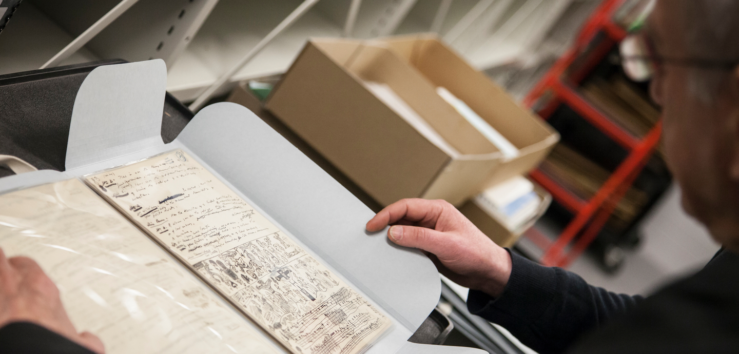 A person reading a handwritten notebook from the Samuel Beckett Archive at the University of Reading