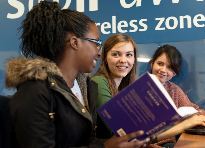 Three female students studying together in the University library.