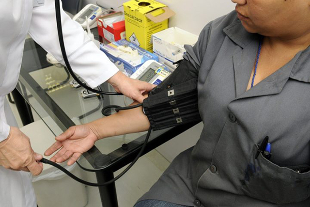 A doctor takes a man's blood pressure using a cuff monitor